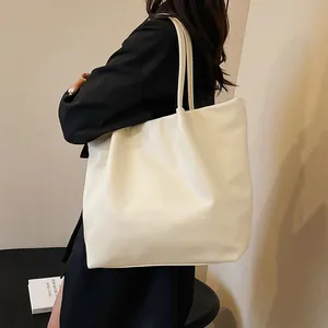 Detailed side view of large beige PU leather bucket bag showing capacity and shoulder straps