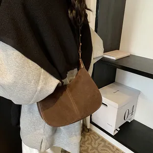 Détail d'un sac hobo en daim marron avec couture centrale et bandoulière réglable pratique