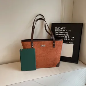 Detailed macro view of brown suede tote bag with leather trim on white marble surface