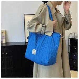 Detail of blue quilted nylon tote bag with drawstring and brand label on shoulder
