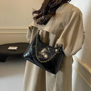 Side view of black quilted shoulder bag with gold chain and glossy faux leather texture
