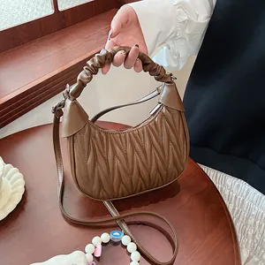Detailed view of dark brown pleated dumpling bag in polished faux leather and handle