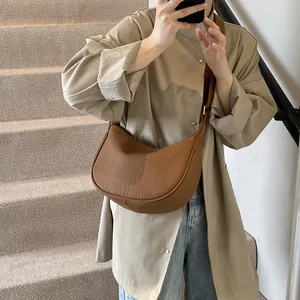 Détail de sac demi-lune marron avec cuir plissé et bandoulière large confortable