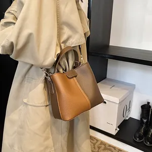 Detail of lychee textured leather bucket bag with fashion logo and metal hardware