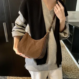 Détails du sac lune en daim marron avec anneaux métalliques dorés et coutures
