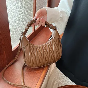 Detail of warm brown pleated cloud bag featuring premium PU texture and soft handle
