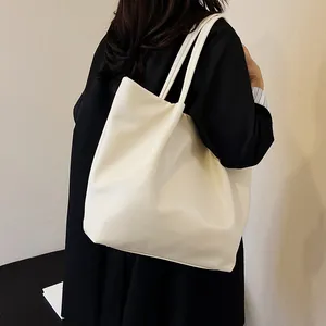 Close-up of creamy white PU leather tote bag showing soft texture and long straps