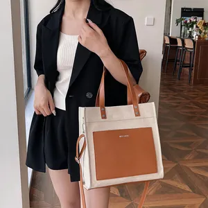Fashionable canvas tote bag with contrast brown leather details and adjustable shoulder strap