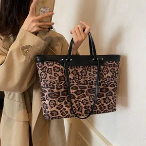 Detailed close-up of leopard print tote bag with dual straps and black leather trim