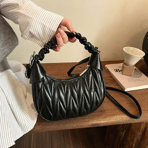 Detailed view of black matelasse cloud bag with pleated handle on wooden table