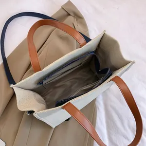 Contrast color canvas tote bag with brown leather straps and spacious blue interior