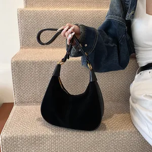 Détail du sac hobo noir en daim avec anneaux dorés et bandoulière en cuir lisse