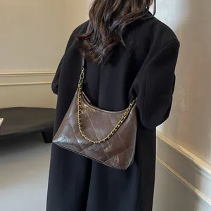 Detail of dark brown quilted rhombic shoulder bag with golden chain and leather strap