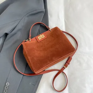 Détail du sac à main en daim rouge rouille montrant la texture mate et le fermoir doré