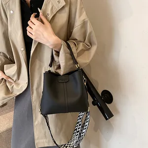 Detail of black lychee grain bucket bag with black and white wavy wide strap for women