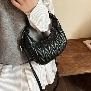 Black ruched half-moon bag with wavy quilting and shoulder strap in lifestyle setting