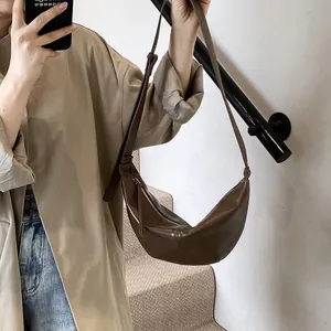 Primer plano de bolso bandolera de media luna marrón oscuro con cremallera plateada elegante