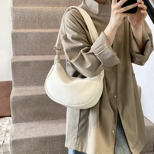 Détail d'un sac à bandoulière plissé blanc cassé avec texture douce et boucle dorée