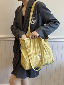 Yellow large capacity striped nylon tote bag with drawstring for women shown on shoulder