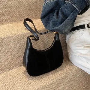 Détail du sac hobo en daim noir et cuir avec fermeture éclair dorée sur marches beiges