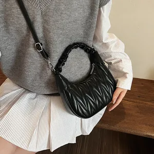 Detail of black pleated cloud bag with silver hardware and adjustable strap on a model