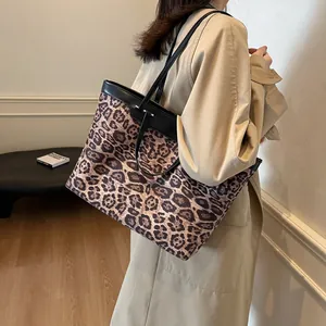 Detail shot of a large leopard print tote bag with black leather straps on a model