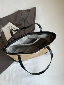 Large beige suede tote bag with black leather straps for elegant office commuting