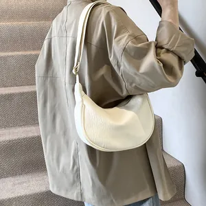 Sac hobo blanc en similicuir texturé porté par un modèle avec bandoulière large