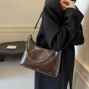 Close-up of a dark brown quilted shoulder bag with gold chain and glossy oil leather texture