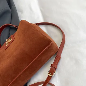 Détail du sac cabas en daim caramel avec fermoir rotatif doré et bandoulière réglable