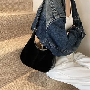 Détail du sac hobo en daim noir avec bandoulière en cuir et fermeture éclair dorée chic
