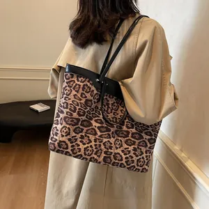 Chic leopard print tote bag with black straps worn by a model in a minimal interior