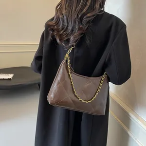 Detail view of retro quilted dark brown shoulder bag with golden chain strap on model