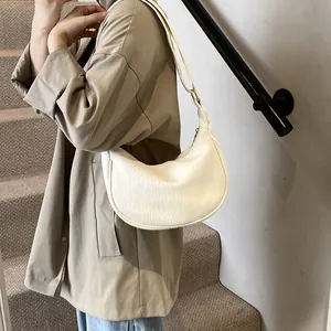 Détail d'un sac à bandoulière demi-lune blanc crème avec cuir texturé et fermeture éclair