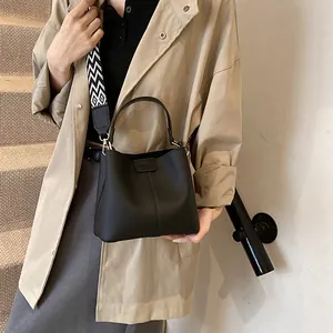 Detail of black lychee grain leather bucket bag with geometric wave pattern strap