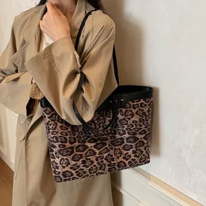 Detail of contrast leopard print tote bag with black trim worn on a beige trench coat