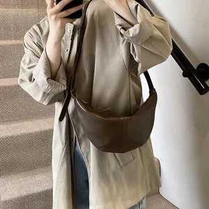 Bolso bandolera de media luna en cuero sintético marrón llevado por una modelo real