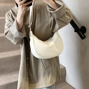 Sac bandoulière demi-lune blanc plissé avec sangle réglable porté par un mannequin