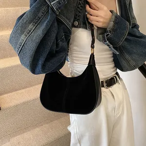 Détail du sac croissant en daim noir avec coutures sur tenue décontractée