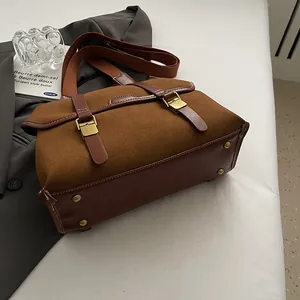 Detail showing high-quality suede texture and metal protective studs on bag base