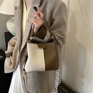 Detail of contrast stitching and woven shoulder strap on a two-tone bucket bag