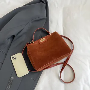 Vue détaillée du sac à main Kelly en daim marron avec fermoir doré et bandoulière