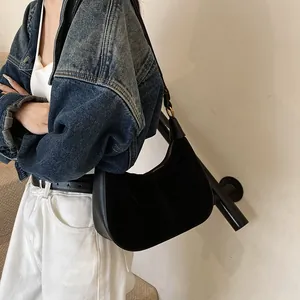 Détail d'un sac hobo noir en forme de croissant avec finition mate porté par un modèle