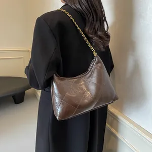 Close-up of brown quilted hobo bag with glossy finish and gold metal chain strap