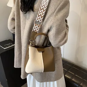 Detail of contrast stitching bucket bag with geometric patterned wide strap