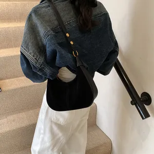 Détail du sac hobo en daim noir avec boucles dorées réglables sur la bandoulière en cuir