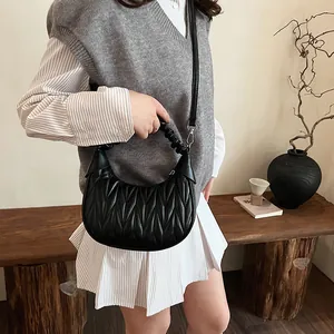 Detail of black pleated dumpling bag with adjustable strap on a female model