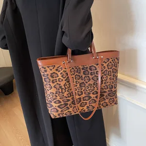 Side view of model carrying leopard print tote bag with brown leather handles