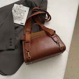 Macro view of retro brown leather bag showing premium texture and brass metal hooks