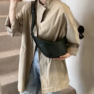 Bolso de cuero verde oscuro combinado con gabardina beige para un estilo diario elegante